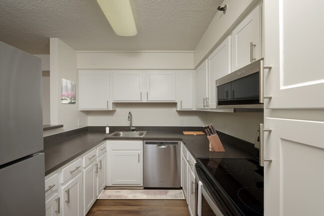 Finish Package III kitchen with white cabinetry, stainless steel appliances, and hard surface plank flooring