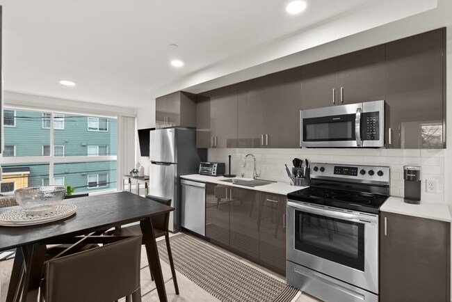 Modern kitchen with stainless steel appliances and open dining space.