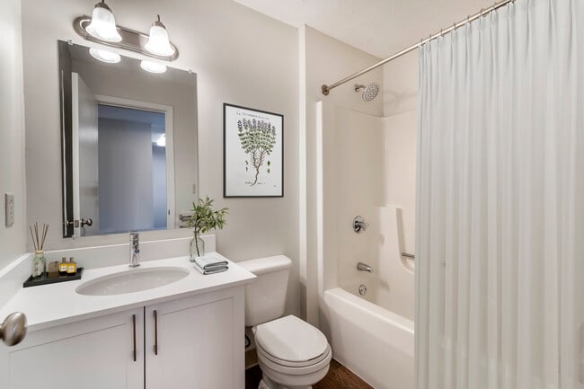 Renovated Package I bath with white laminate countertops, white cabinetry, and hard surface flooring