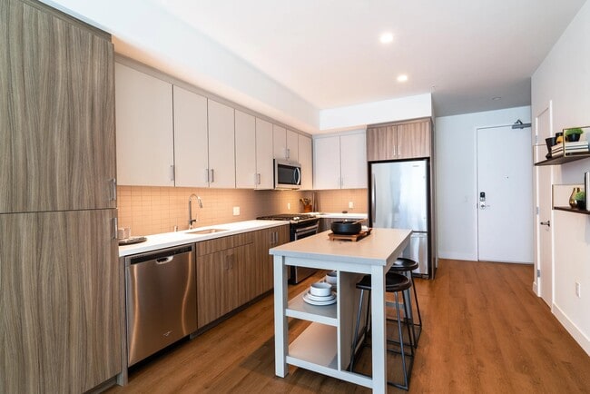 Kitchen with dual-tone cabinetry, stainless steel appliances, quartz surfaces, and a central island that adds flexibility for dining and meal prep.