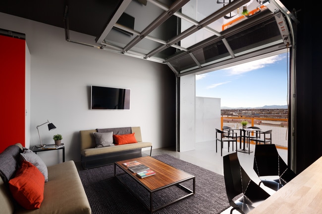 Living room with operable garage door leading to private balcony - Freight Residences