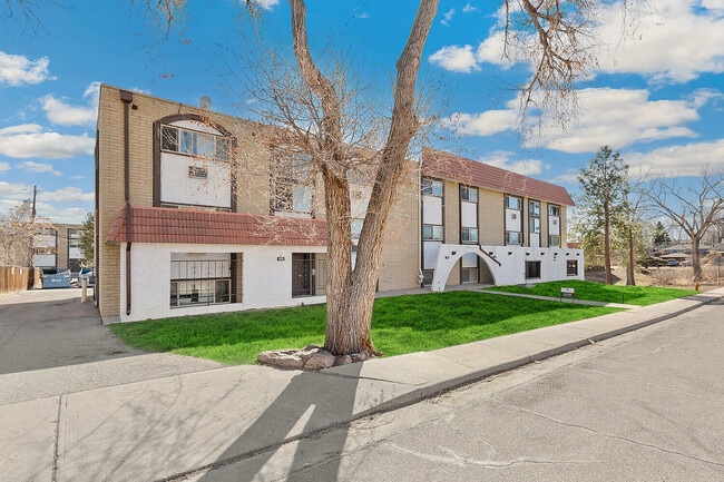 Charming apartment building with a classic red-tiled roof and well-maintained exterior, nestled in a serene neighborhood with lush green lawns and clear blue skies. - Country Club