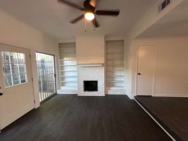 Bright living room- oversized windows, built-in shelving, decorative white-painted brick fireplace - 7700 Creekbend Dr Unit 124
