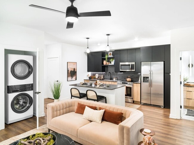An open living area at Modera Nations in Nashville features wide-plank flooring, an island kitchen, and in-home laundry for seamless everyday living.