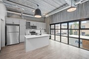Elegante cocina urbana con electrodomésticos modernos, armarios estilizados y amplios ventanales que ofrecen abundante luz natural.