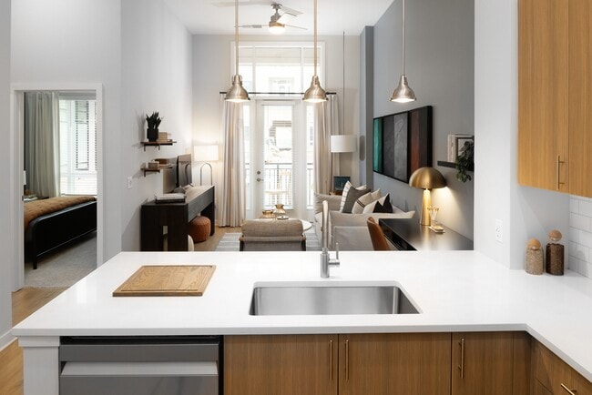 Kitchen and living area with oak cabinetry, white quartz countertops, and pendant lighting - Avalon Durham