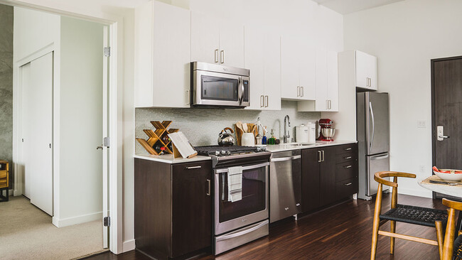 Well appointed kitchen featuring espresso lower cabinetry and white upper cabinetry - Blossom Plaza Apartments