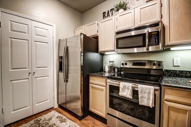 Stunning kitchen with hardwood style flooring, light colored cabinetry and stainless steel appliances