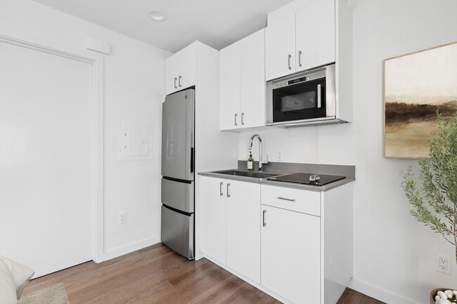 Classic Package II kitchen with white cabinetry, grey quartz countertops, stainless steel appliances, and hard surface flooring