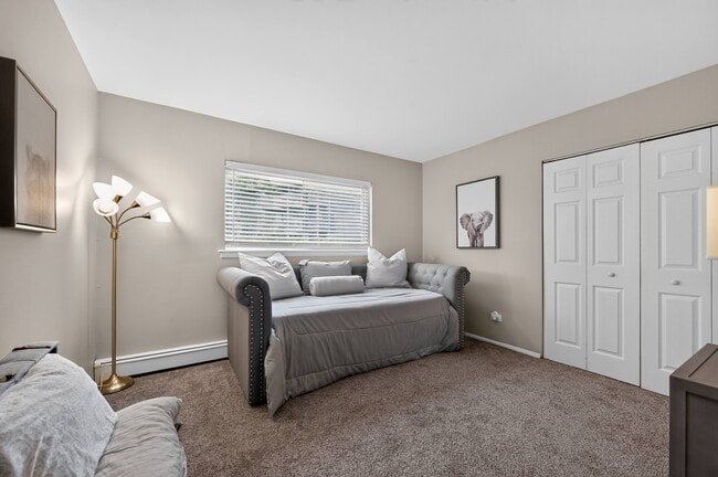 Unwind in a cozy bedroom featuring warm lighting and wall art at Renaissance at Carol Stream in Carol Stream, IL. - Renaissance at Carol Stream