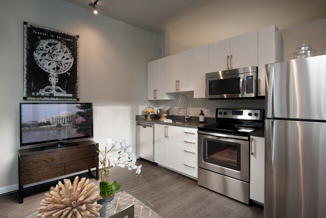 Cocina de concepto abierto con gabinetes blancos, encimeras de cuarzo, electrodomésticos de acero inoxidable y pisos de superficie dura - Avalon Dunn Loring