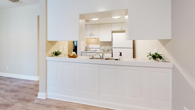 Bright, modern kitchen with a marble countertop, white cabinetry, and sleek appliances perfect for culinary creativity. - Chateau of Tampa