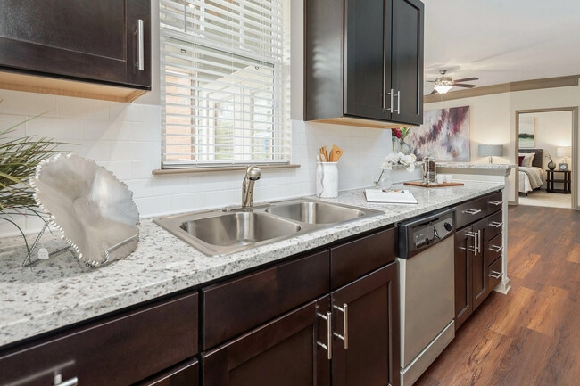 Modern apartment kitchen with granite countertops, stainless steel appliances, and rich cabinetry—open-concept living in Charlotte.