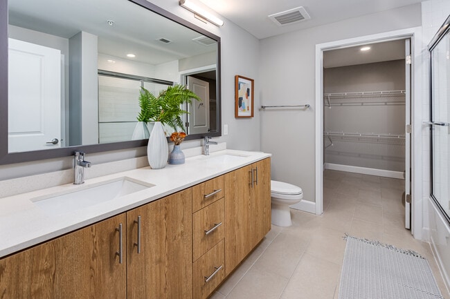 Dual vanity bathroom with quartz countertop and spacious, walk-in closet