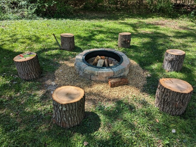 Un área de fogata en el patio trasero con asientos de leña rústica, perfecta para relajarse al aire libre. - 2406 Crockett Cir