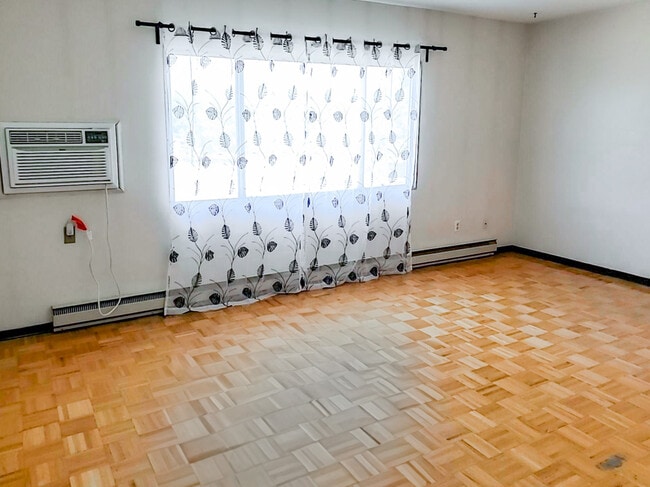 Enjoy a bright and airy living space at 1025 Munroe Apartments, featuring large windows that let in plenty of natural light. - 1025 Munroe Avenue