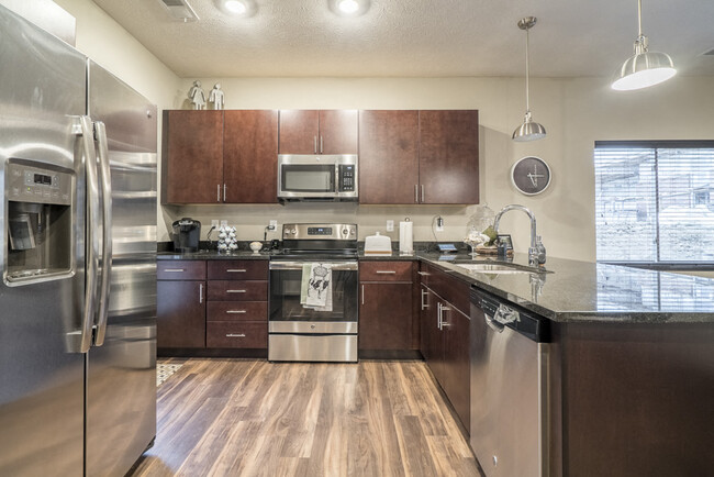 Our traditional design scheme features rich, dark cabinetry with darker granite countertops. - The Villas at Falling Waters Apartments