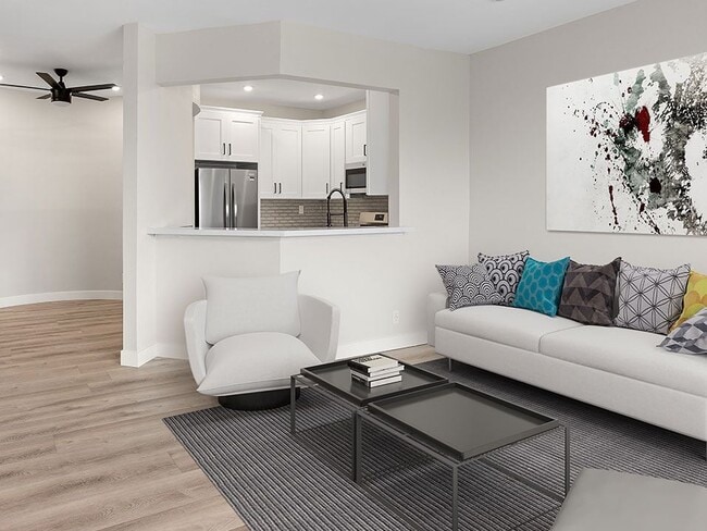Hardwood floored living room with view of kitchen and dining area.