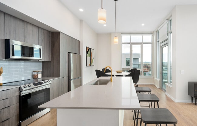 Signature Collection Kitchen with dark cabinetry, marbled quartz countertops and backsplash, upgraded stainless steel appliances, pendant lighting. - Avalon Governors Park Apartments