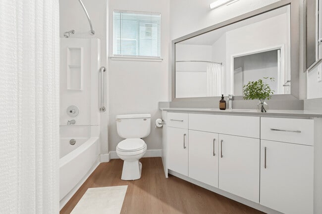 Renovated Package I bath with white cabinetry, grey quartz countertops, and hard surface flooring