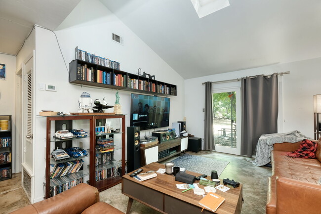 Living room with vaulted ceiling and skylight, sliding door to private back yard - 1602 Valleyridge Dr Townhome