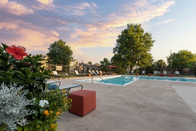 Relax by the pool at The Lakes, with lounge chairs and a table offering a peaceful retreat beside the refreshing water.