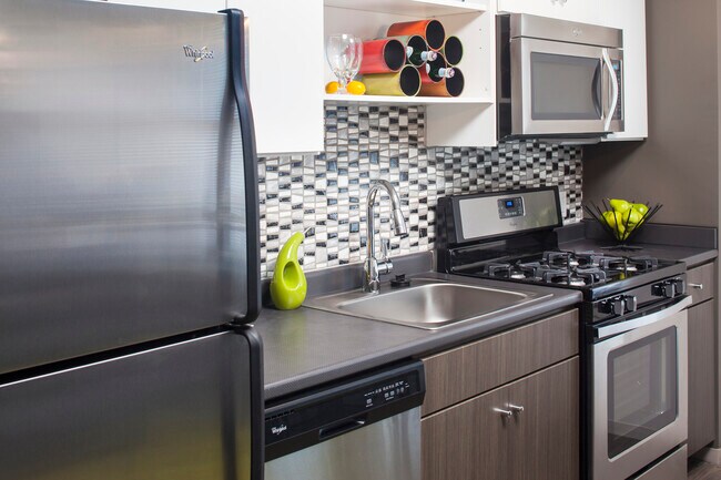 Classic Package II kitchen with stainless steel appliances, dark laminate countertops, white and brown cabinetry, tile backsplash, and hard surface flooring