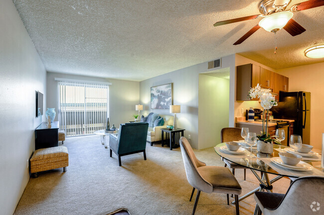 Model apartment dining area with a ceiling fan and a view of the living area and kitchen. - Montebello Gardens Rental