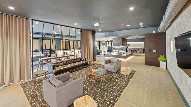 Entertainment lounge with tile floor, comfortable seating, and large TV.
