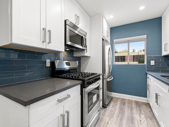 Blue cocina con azulejos con electrodomésticos de acero inoxidable, refrigerador, horno, y un horno de microondas.