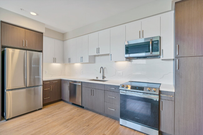 This full kitchen has a large sink, French-door fridge, dishwasher, microwave, stovetop oven, and a - Evoc Hillcrest Apartments