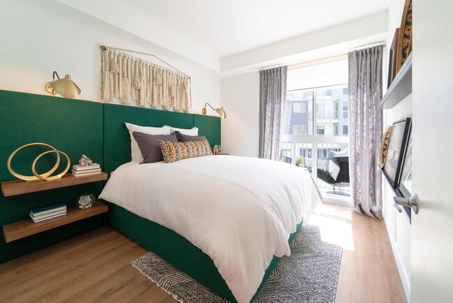 Bedroom with a private balcony, wood-style plank flooring, and abundant natural light that creates a bright, inviting retreat.