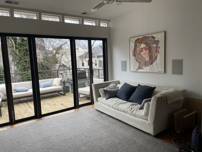 High ceilings with Restoration Hardware sofa and cashmere pillows opens out to large deck with Restoration Hardware outdoor furniture
