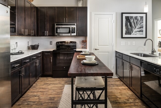 Kitchen with espresso cabinetry, granite countertops, tile backsplash, and hard-surface vinyl plank flooring - Avalon Lakeside