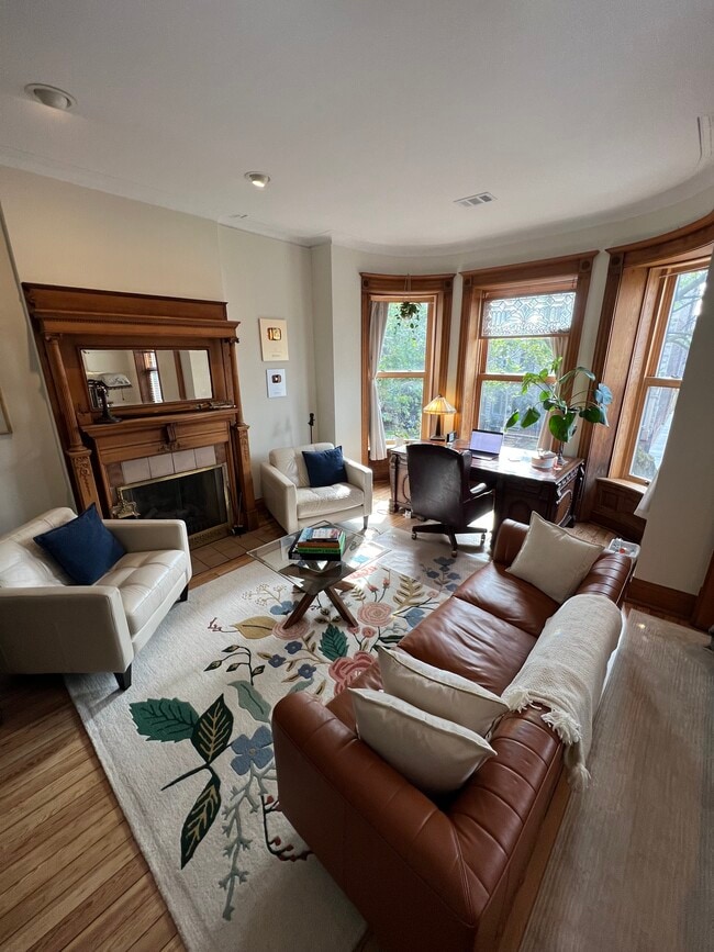 Beautiful front living room with original fireplace, original hardwood floors & curved windows - 938 W Newport Ave
