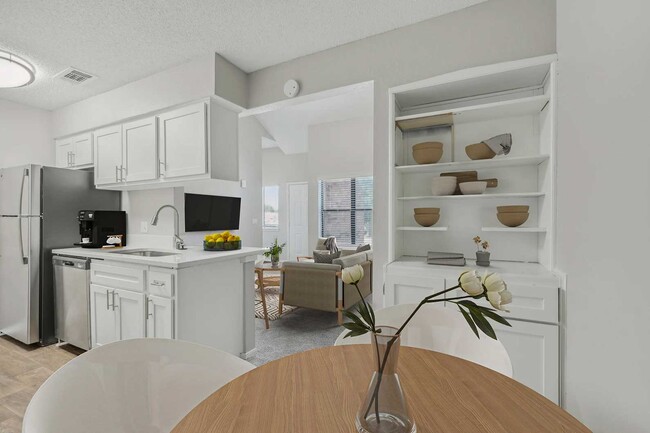 Kitchen with white cabinets, stainless steel appliances, quartz countertops, built-in shelving, and open living area