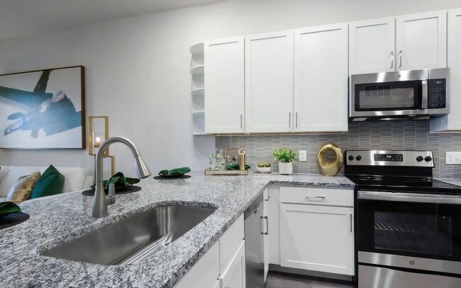 Cocina con encimeras de granito, electrodomésticos de acero inoxidable y elegante protector contra salpicaduras. - The Harper