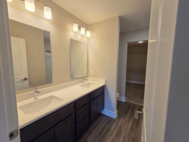 Townhome primary bathroom with dual sinks, shower, and closet. - Flats at Sugar Run