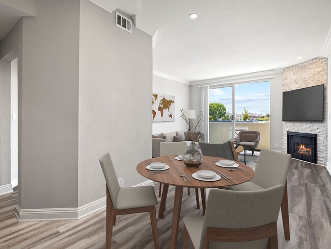 Hardwood floored dining room with view of balcony and stone walled fireplace.