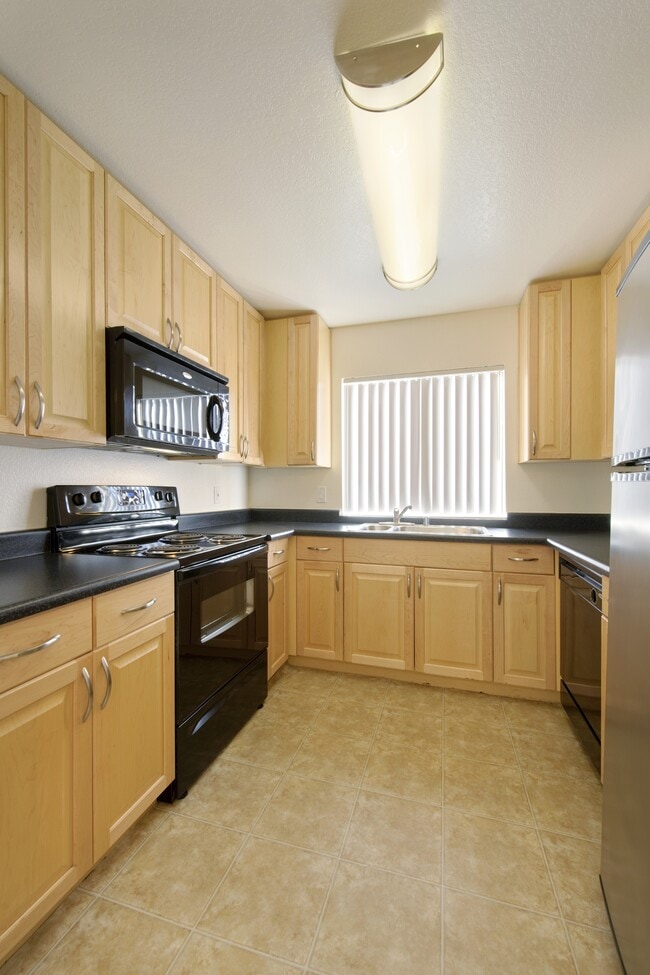 Kitchens with black appliances, black laminate countertops, and maple cabinetry