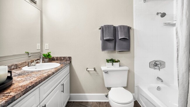 Step into our revitalized bathroom retreats, featuring deluxe granite-style countertops, grand wall-to-wall mirrors, and wood-style flooring with white tile surround for a luxurious and vibrant experience.