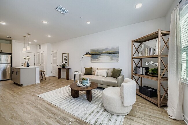 Contemporary open-plan living room with a cozy sofa, elegant decor, chic shelving, and a modern kitchen with stainless steel appliances.