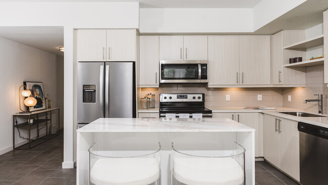 Kitchens with custom cabinetry, bar seating, and built-in shelves - Modera Edgewater Apartments