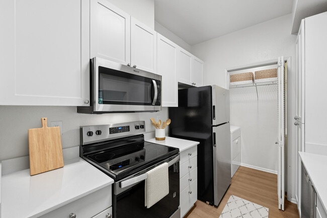 Renovated Package I kitchen with updated stainless steel appliances, white cabinetry, white quartz countertops, and hard surface flooring