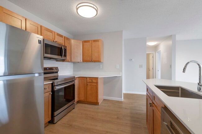 Renovated Package I kitchen with stainless steel appliances, white quartz countertops, maple cabinetry, white tile backsplash, and hard surface flooring