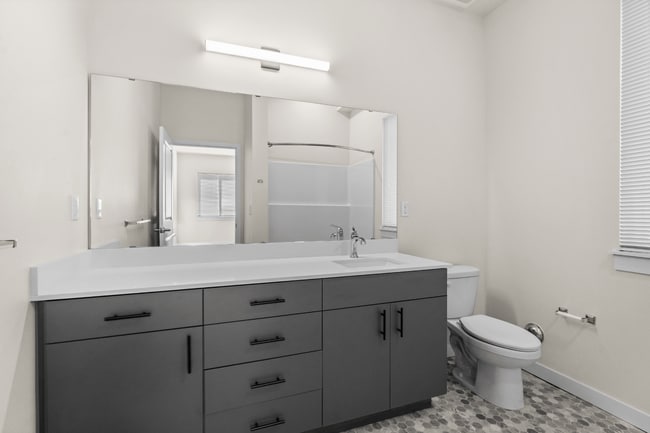 Start your day in a stylish bathroom with modern finishes, generous storage, and a spacious vanity area. - 27 West Apartments