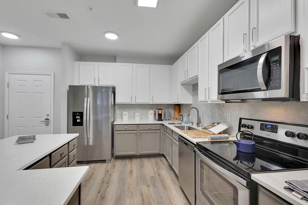 Modern kitchen with sleek stainless steel appliances, elegant white cabinetry, and stylish wood flooring, perfect for culinary enthusiasts.