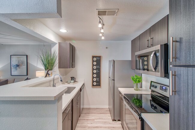 Kitchen with Espresso Cabinetry and Stainless Steel Appliances - Stonelake at the Arboretum Apartments