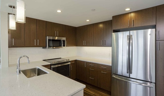 Open kitchens with stainless steel appliances, ample quartz countertop space, and French door refrigerator - Park Towne Place