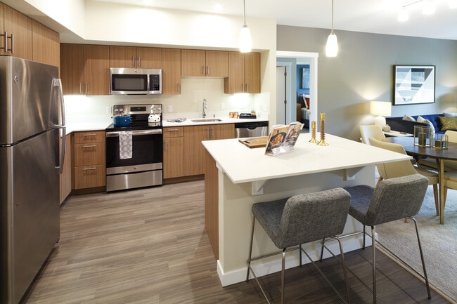 Phase I - Scheme B Kitchen with oak cabinetry, stainless appliances, white quartz countertops, and hard surface flooring